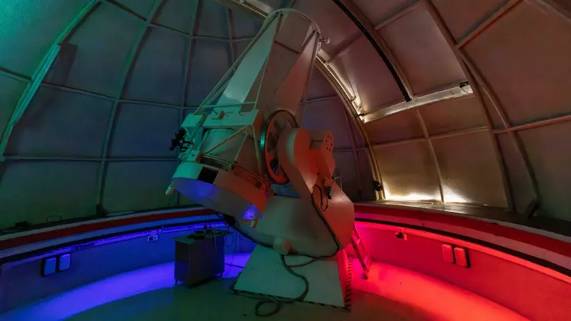Interior de cúpula con telescopio iluminado en colores