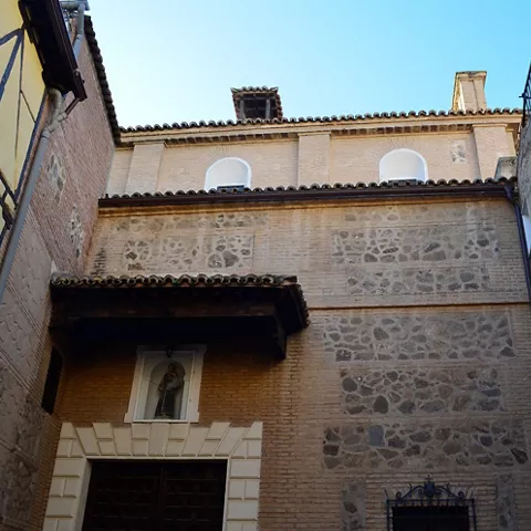 Fachada de convento entre muros de piedra y ladrillo.