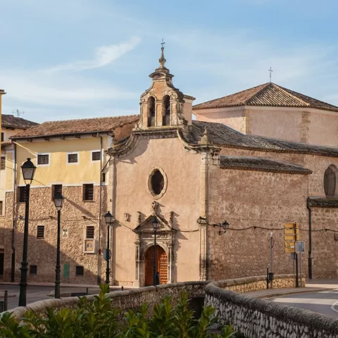 Conjunto conventual junto a puente y curva de calle.