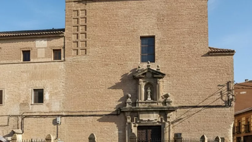 Fachada de ladrillo con espadaña y hornacina sobre la puerta.