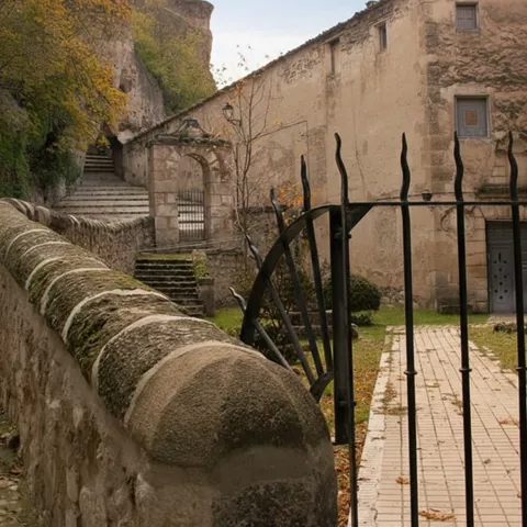Camino empedrado con verja y muros de piedra