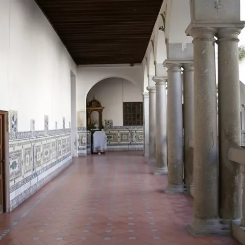 Corredor con columnas de piedra y zócalo de azulejos