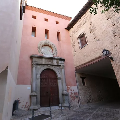 Fachada histórica con portada de piedra en una calle estrecha.