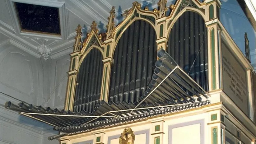 Órgano antiguo con tubos metálicos y decoración pintada.