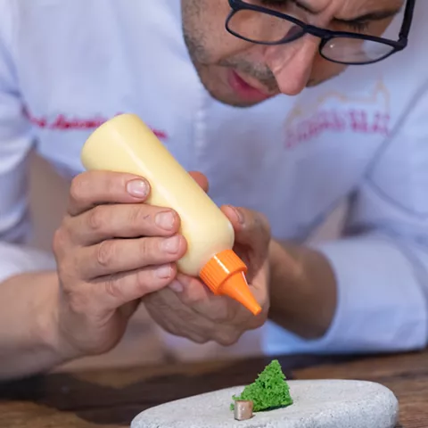 Chef aplicando salsa con biberón