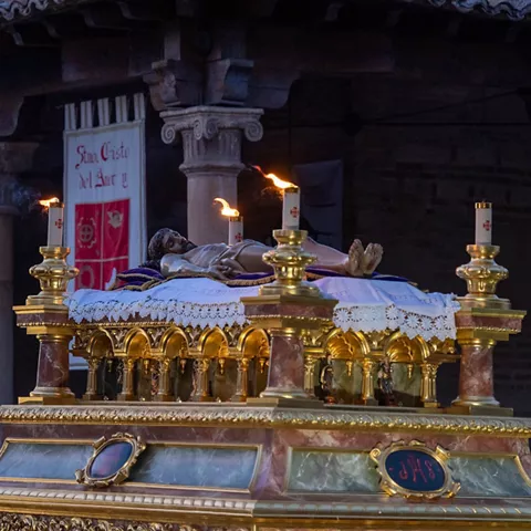 Cristo yacente sobre urna con cirios.