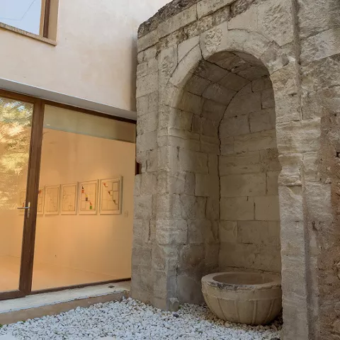 Patio con arco de piedra y suelo de grava blanca.