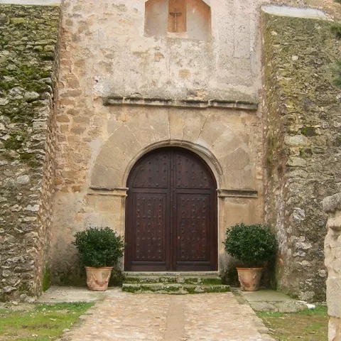 Portada de piedra con arco y puerta de madera.
