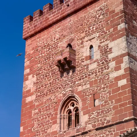Detalle de matacán y ventanal gótico en torre de ladrillo