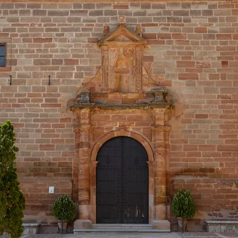 Puerta de iglesia con arco de piedra y fachada de mampostería.