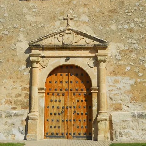 Puerta de madera tallada en fachada de piedra.