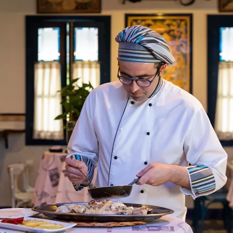 Cocinero sirviendo pescado en comedor tradicional
