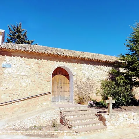 Ermita de piedra con puerta de madera y escalinata.