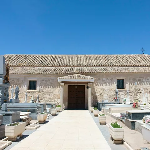 Edificio de piedra junto a cementerio con nichos y cruces