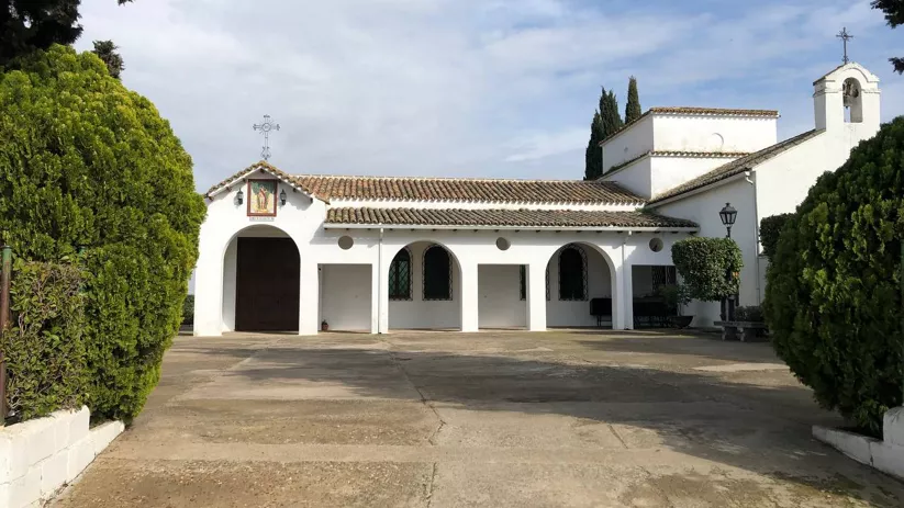 Ermita blanca con patio y vegetación alrededor
