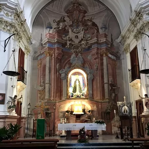 Altar barroco de iglesia con imagen iluminada al fondo.