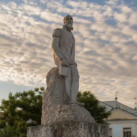 Escultura en piedra sobre pedestal en espacio abierto.