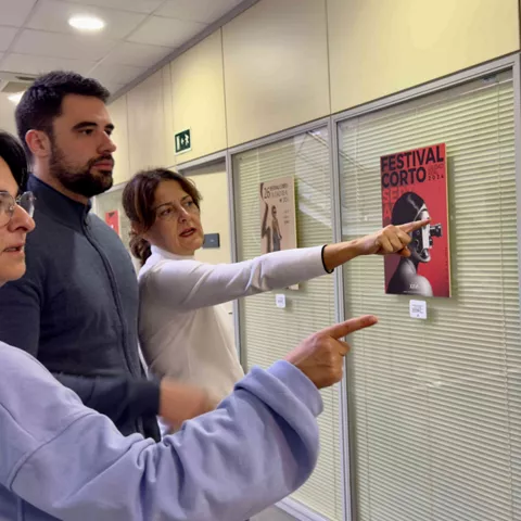 Personas observando carteles gráficos en una exposición interior.