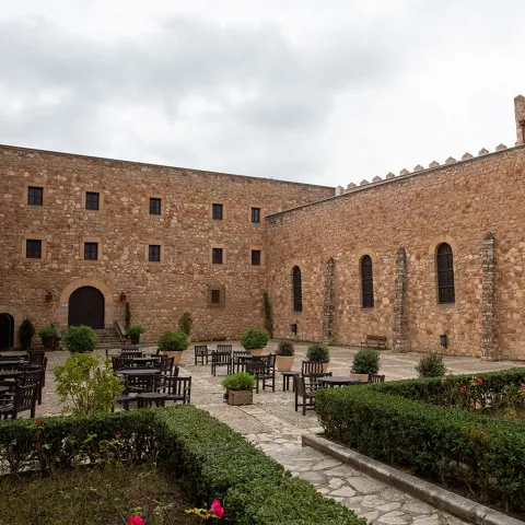 Patio amurallado con mesas y jardines geométricos.