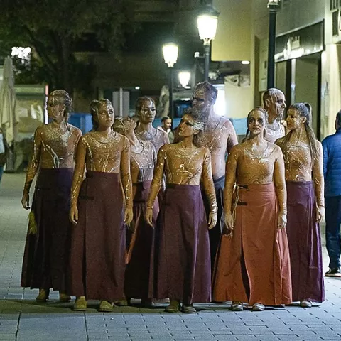 Acción escénica nocturna con grupo de intérpretes en la vía pública.
