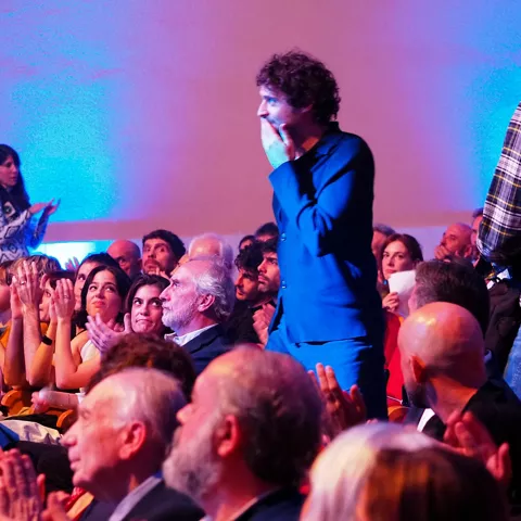 Persona emocionada levantándose entre aplausos del público