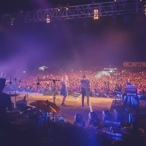 Vista desde el escenario hacia una multitud durante actuación musical nocturna.
