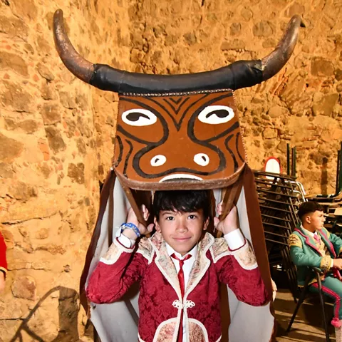 Niño con traje tradicional y máscara de animal