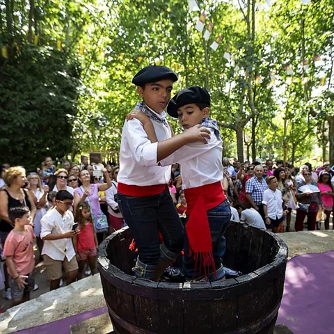 Dos niños bailan un baile tradicional sobre un lagar rodeados de espectadores.
