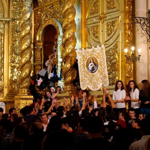 Estandarte sostenido por jóvenes junto a retablo barroco.
