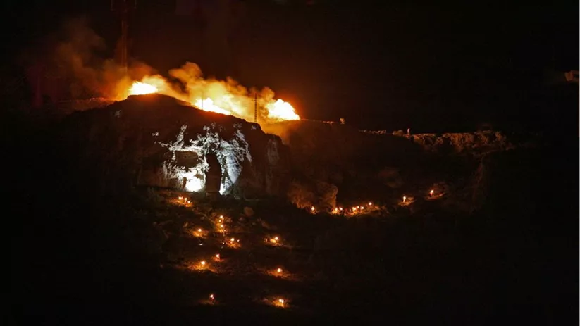 Colina iluminada por hogueras y antorchas durante una celebración nocturna.
