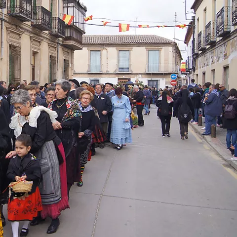 Procesión de personas con trajes tradicionales por una calle