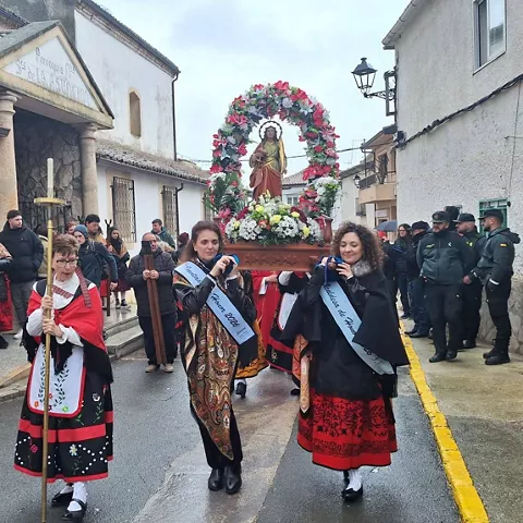Procesión por calle con estandartes y vestimenta típica.