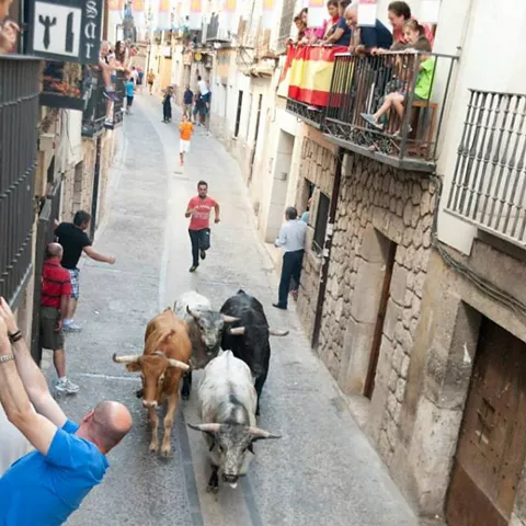 Encierro tradicional de toros por calle con vecinos en balcones