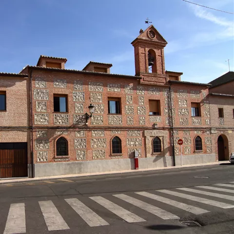 Fachada de ladrillo con campanario junto a la calle