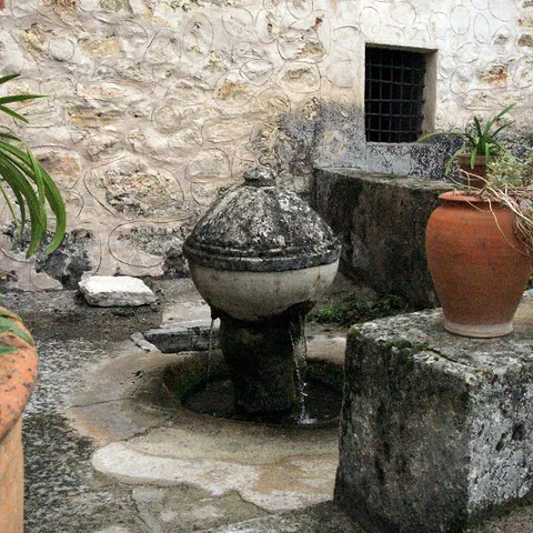Fuente antigua en patio de piedra.