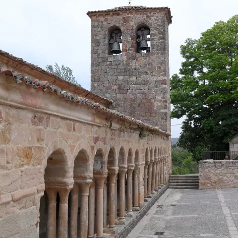 Torre de piedra junto a galería de arcos.