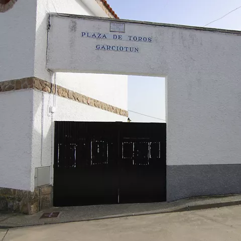 Entrada blanca con portón negro a recinto taurino