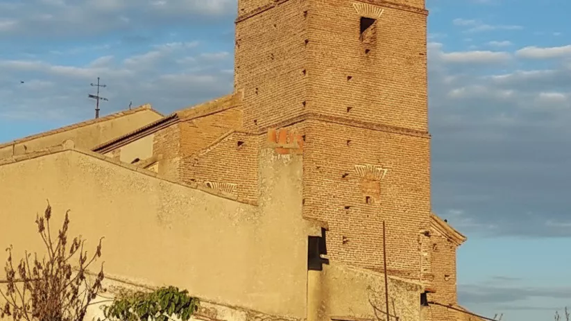 Campanario de ladrillo al atardecer con nido en la cima