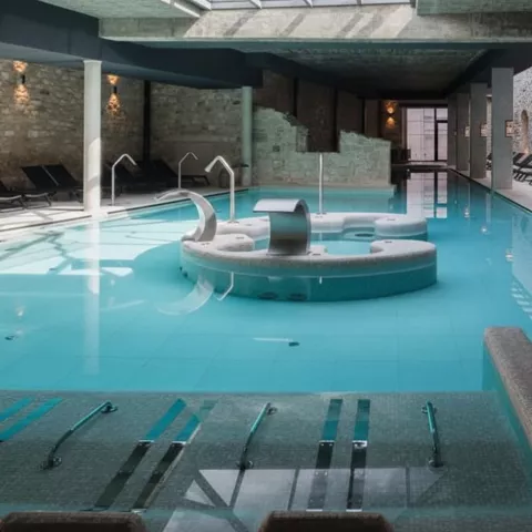 Spa interior con piscina termal y tumbonas.