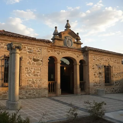 Fachada de piedra al atardecer con columnas y entrada porticada.