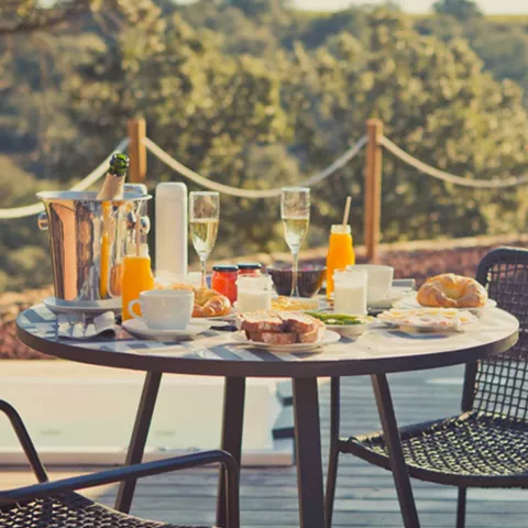 Mesa con desayuno en una terraza exterior con vistas al paisaje.