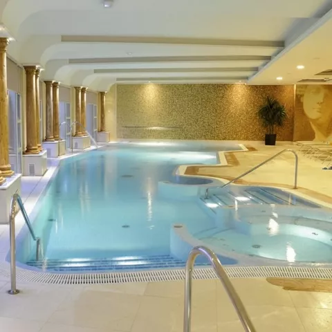 Piscina interior climatizada con columnas y zona de hidromasaje.