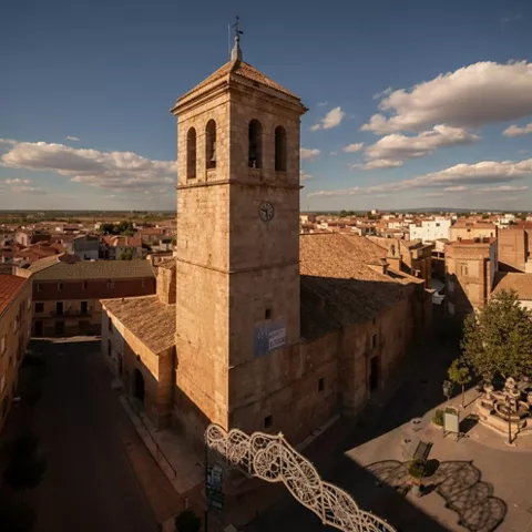 Vista aérea de campanario de piedra y plaza cercana, con el casco urbano alrededor.