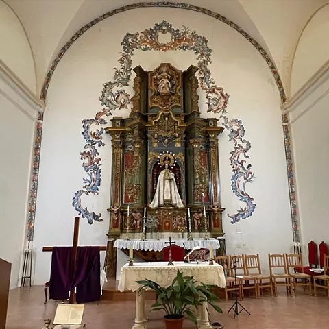 Altar mayor con retablo barroco y escultura religiosa en el centro.