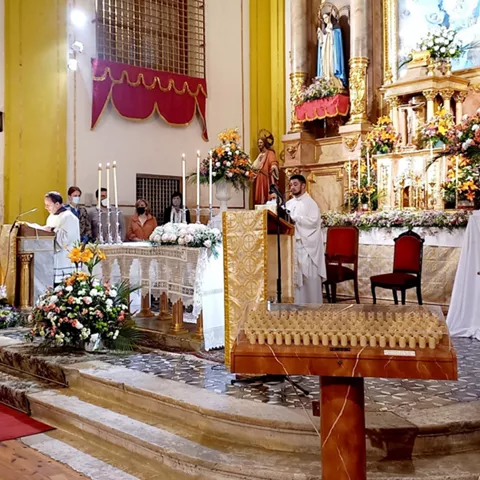 Celebración religiosa con altar floral y velas.