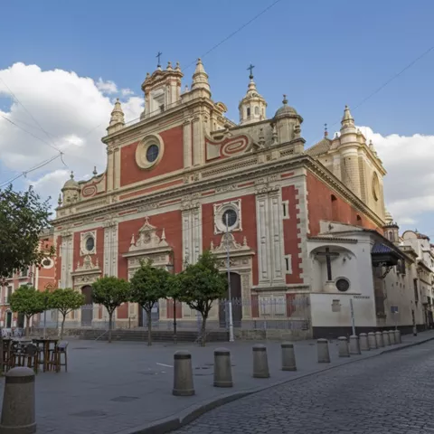 Vista lateral de templo monumental en plaza amplia con árboles alineados.