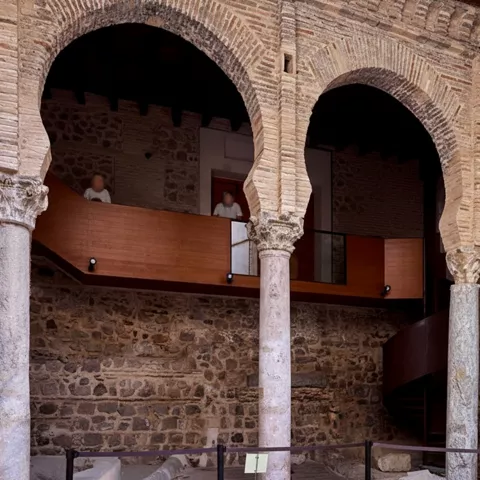 Patio interior con arcos de ladrillo y restos arqueológicos.