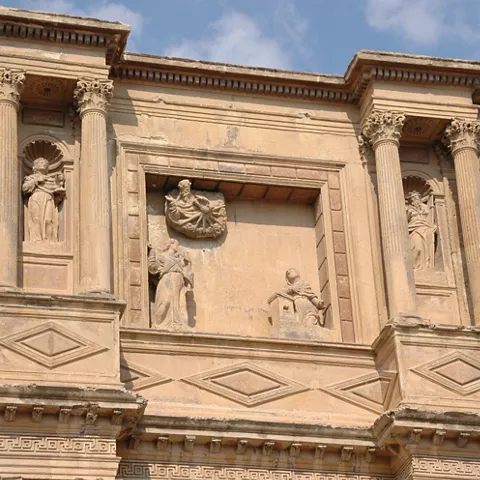 Detalle de portada de piedra con columnas, hornacinas y relieves escultóricos.
