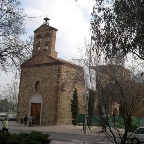 Edificio religioso de nave única con espadaña y entorno arbolado.