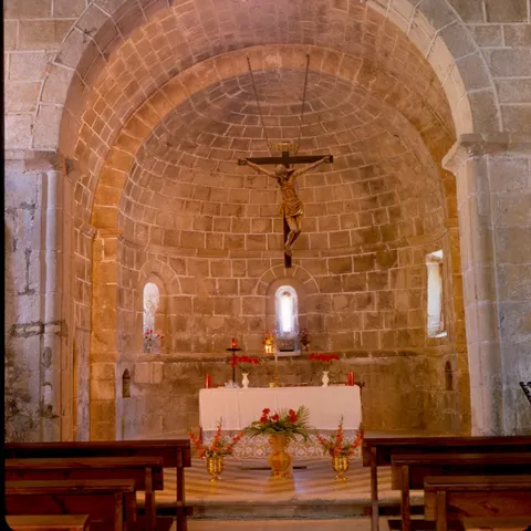 Interior de iglesia románica con altar y ábside.